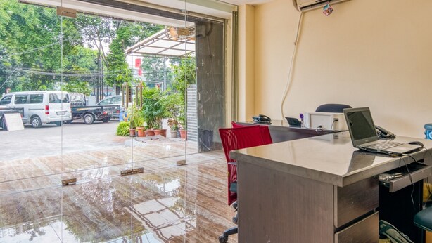 An office with a glass door leading outside, a desk with a laptop, and an air conditioning unit on the wall. - RedDoorz @ Tebet Barat 2 (Jakarta)