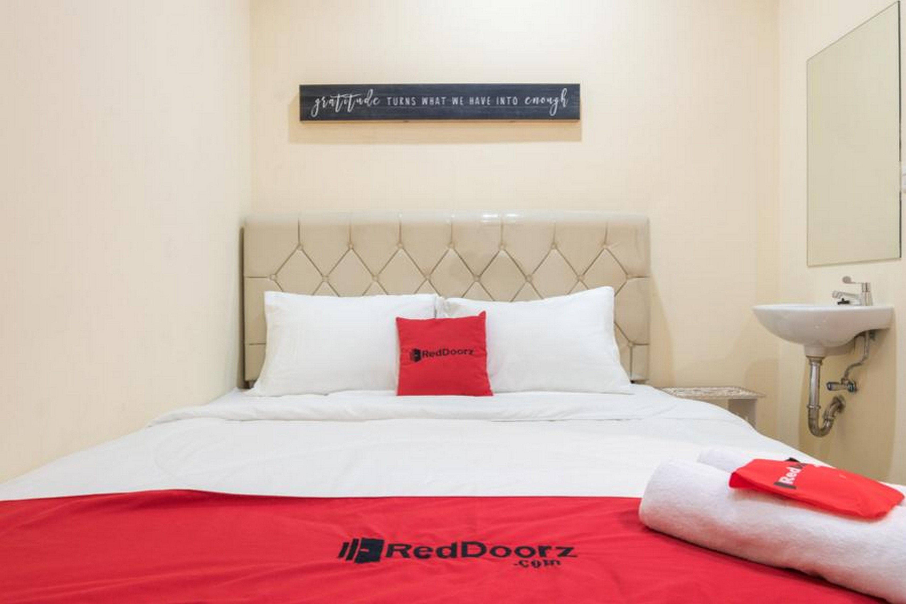 A hotel room with a bed, a pillow, a wall sign, a sink, and a towel.