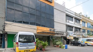 A building with a large glass facade, a parked van, and several potted plants in front. - RedDoorz @ Tebet Barat 2 (Jakarta)