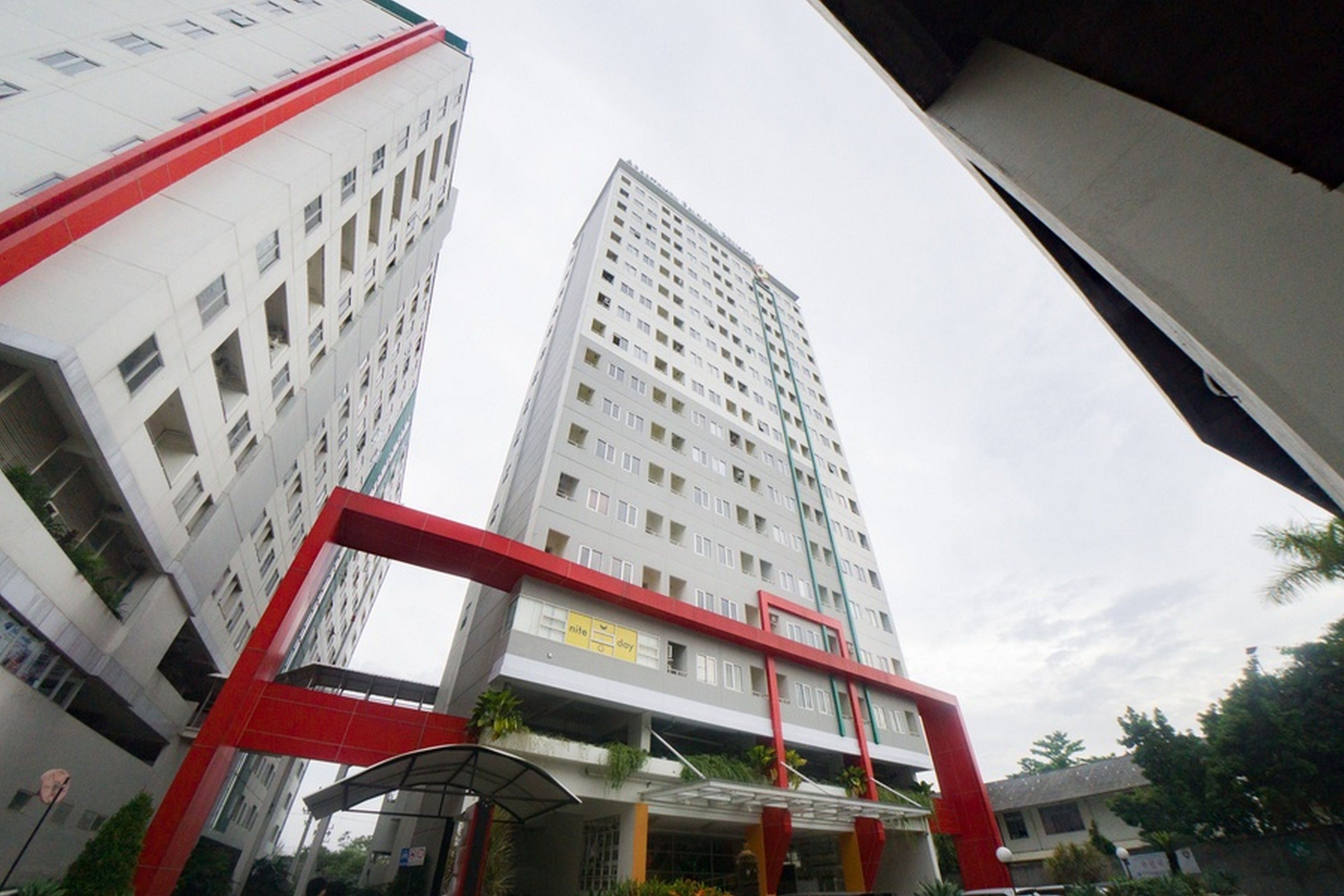 A high-rise building with a red and white facade, multiple balconies, and a visible sign indicating a hotel.