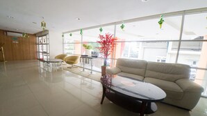 A spacious lobby with a sofa, a round table, and a chair. - RedDoorz Apartment near Bundaran Satelit Surabaya (Surabaya)