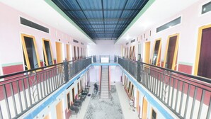 A multi-level atrium with a central staircase, balconies, and a patterned floor. - RedDoorz Syariah near Mall Roxy Banyuwangi 2 (Banyuwangi)