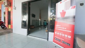 A hotel entrance with a large red banner advertising affordable accommodation. - RedDoorz Syariah near Mall Roxy Banyuwangi 2 (Banyuwangi)