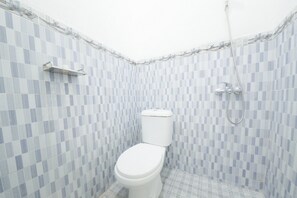 A bathroom with a white toilet, a shower, and a tiled wall.