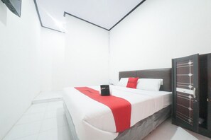 A modern hotel room with a neatly made bed, a bedside table, and a wardrobe.