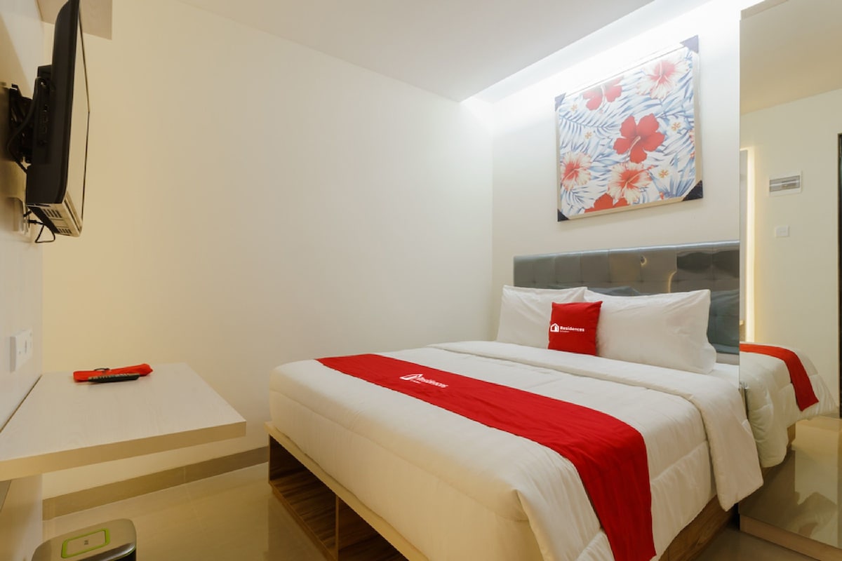 A hotel room with a bed, a desk, and a television mounted on the wall.