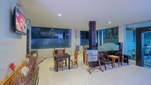 Un vestíbulo de hotel moderno con un gran ventanal, un televisor montado en la pared y una recepción.