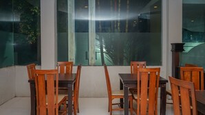 Un comedor con mesas y sillas de madera, ventanas amplias con vistas a la vegetación y un diseño interior moderno.