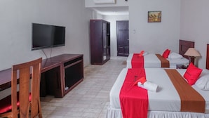 Habitación de hotel con dos camas, televisión, escritorio y armario.