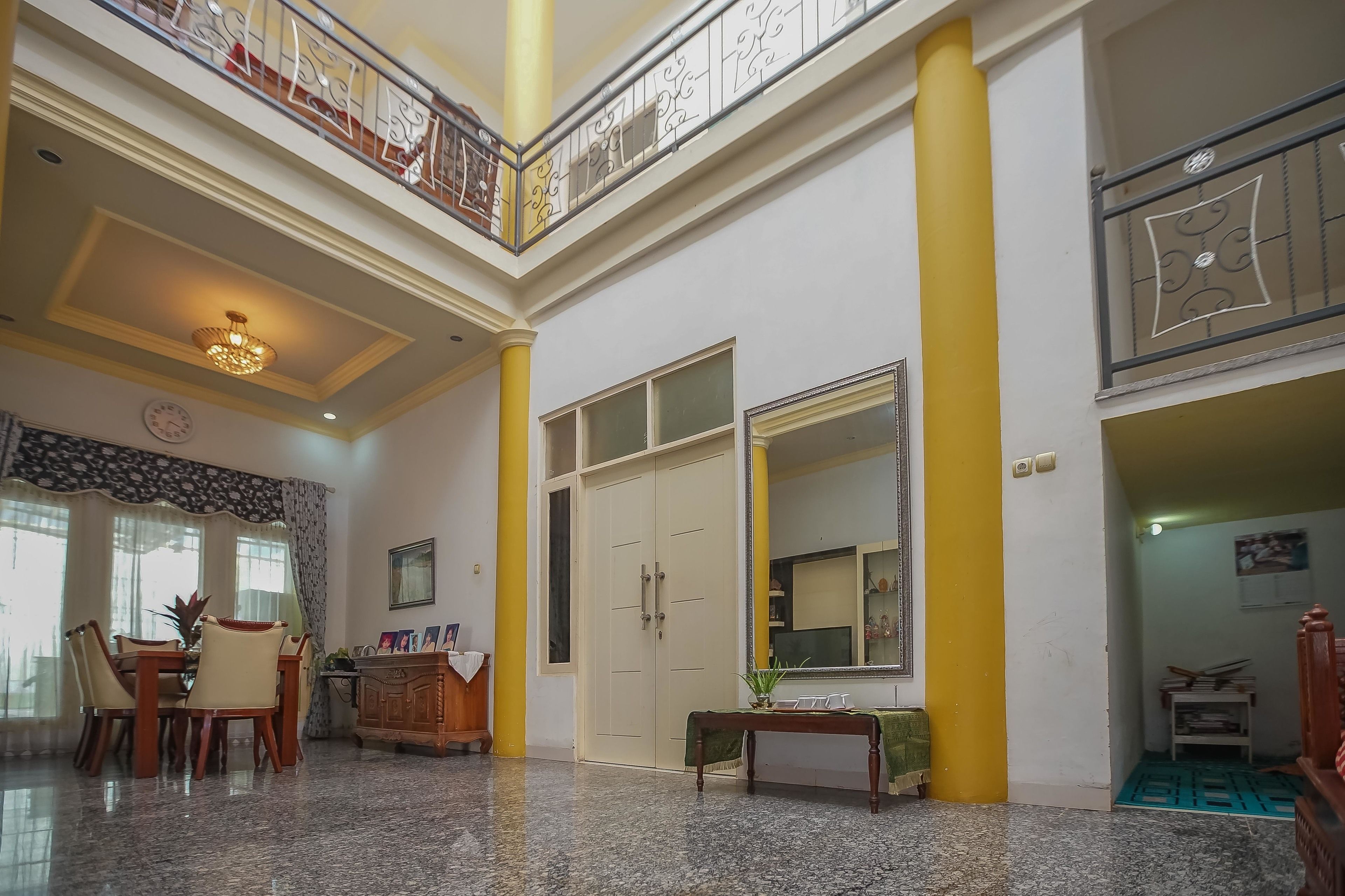 A spacious living area with a high ceiling, a dining table, and a large mirror.