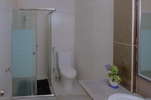 A bathroom with a glass-enclosed shower, a toilet, and a small potted plant on the countertop. - RedDoorz Syariah near Museum Lambung Mangkurat 2 (Banjarbaru)