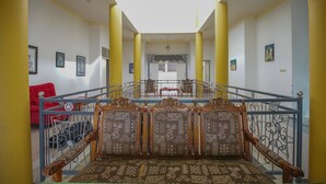 A spacious interior with a central staircase, a red sofa, and patterned seating.