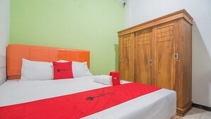 Habitación de hotel con cama, armario y el logotipo de RedDoor en la colcha.
