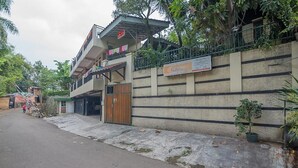 Un edificio de dos plantas con un balcón, un letrero y una entrada protegida por una reja.