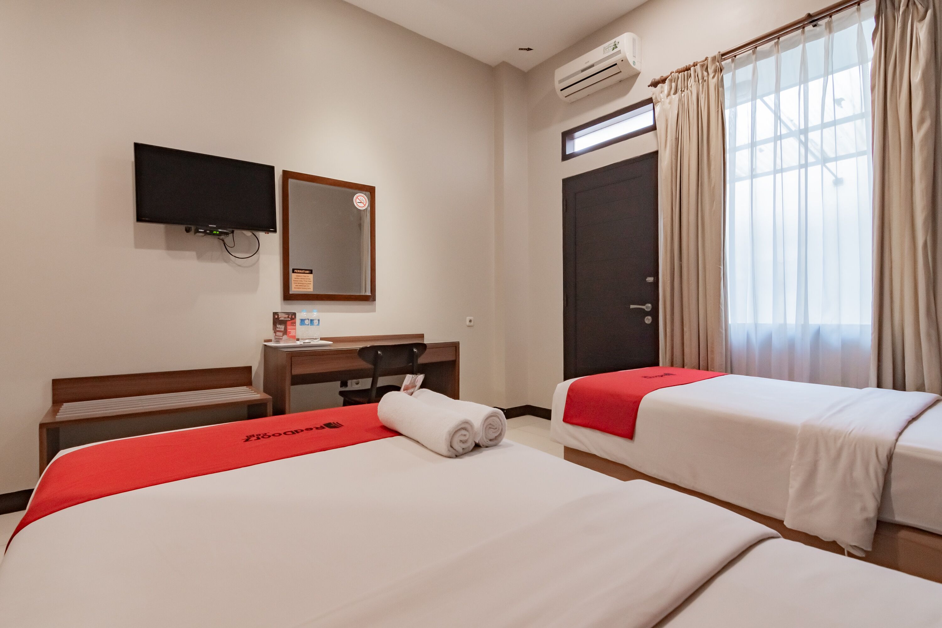 Habitación de hotel con dos camas, un escritorio, un televisor y aire acondicionado.