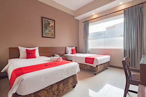 A hotel room with two beds, a desk, and a chair. - RedDoorz near Simpang Dago 2 (Bandung)