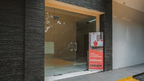 A hotel entrance with a glass door, a black textured wall, and a yellow tactile paving strip. - RedDoorz Plus near Plaza Blok M (Jakarta)