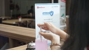A person using a hand sanitizer dispenser in a hotel setting. - RedDoorz Plus near Plaza Blok M (Jakarta)