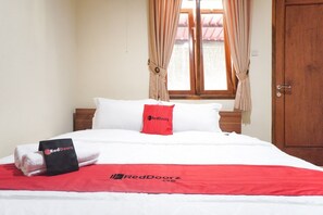 Una habitación de hotel con una cama bien hecha, una ventana con cortinas y una puerta de madera.