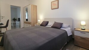 A bedroom with a large bed, bedside tables with lamps, a wardrobe, and a mirror. - Holiday apartment "Dunja", only 500m from the beach (Pula)
