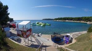 A beachside area with a clear view of the sea, inflatable water toys, a trampoline, and a small kiosk. - Holiday apartment "Dunja", only 500m from the beach (Pula)