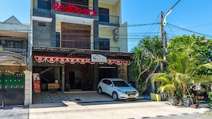 Un bâtiment à deux étages avec une enseigne rouge sur laquelle on peut lire « RedDoorz ».