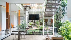 A modern indoor space with a central water feature, seating areas, and a large flat-screen TV. - Reddoorz Syariah Near Transmart MX Malang (Malang)