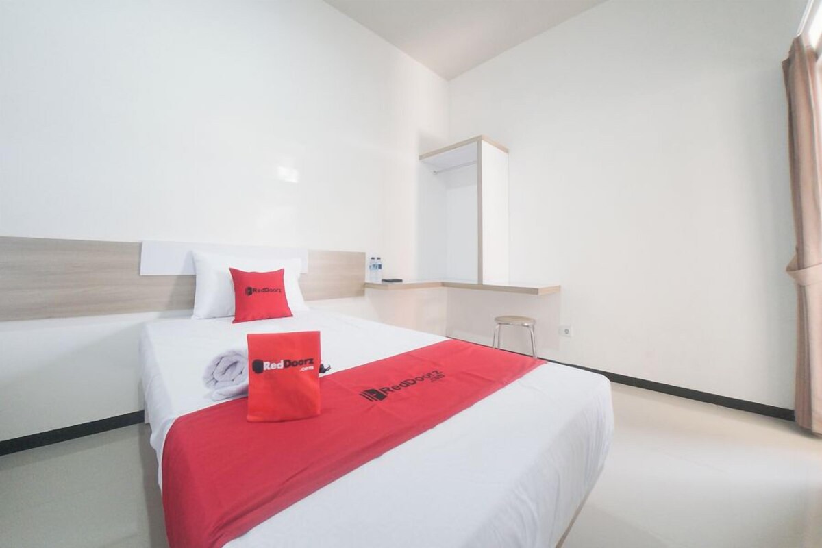 Une chambre d’hôtel avec deux lits, un grand miroir et une couverture rouge ornée du logo Red Doorz.