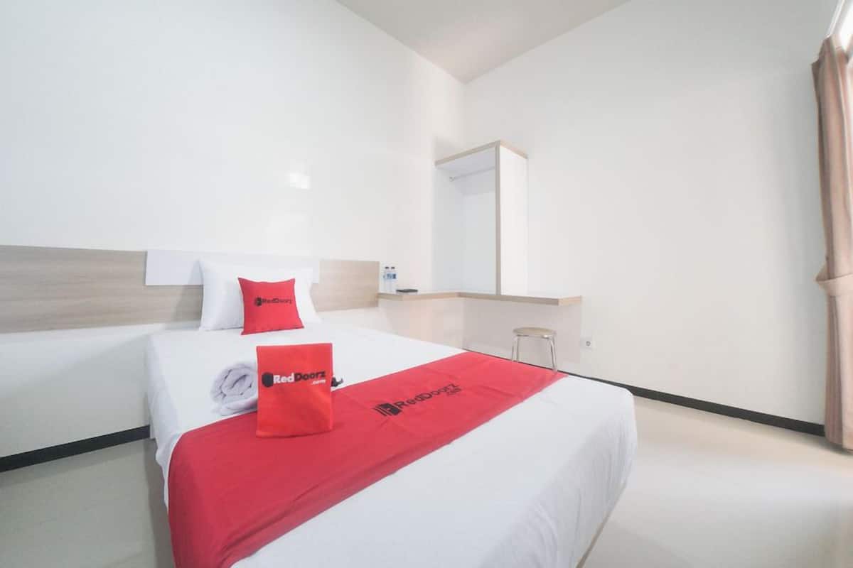 Een hotelkamer met twee bedden, een grote spiegel en een rode bedspread met het logo van Red Doorz.