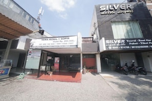 A building with a sign for 'SEWA MOBIL + SOPIR' and 'SILVER' services including airport shuttle.