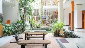 A spacious indoor area with a wooden table, exercise equipment, and various potted plants. - Reddoorz Syariah Near Transmart MX Malang (Malang)