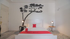 A bedroom with a bed, a nightstand, a wall-mounted tree decal, and two bedside lamps. - RedDoorz near UPI Setiabudi 2 (Bandung)