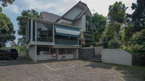 A modern two-story building with a cafe sign, a gated entrance, and a parking area. - RedDoorz near UPI Setiabudi 2 (Bandung)