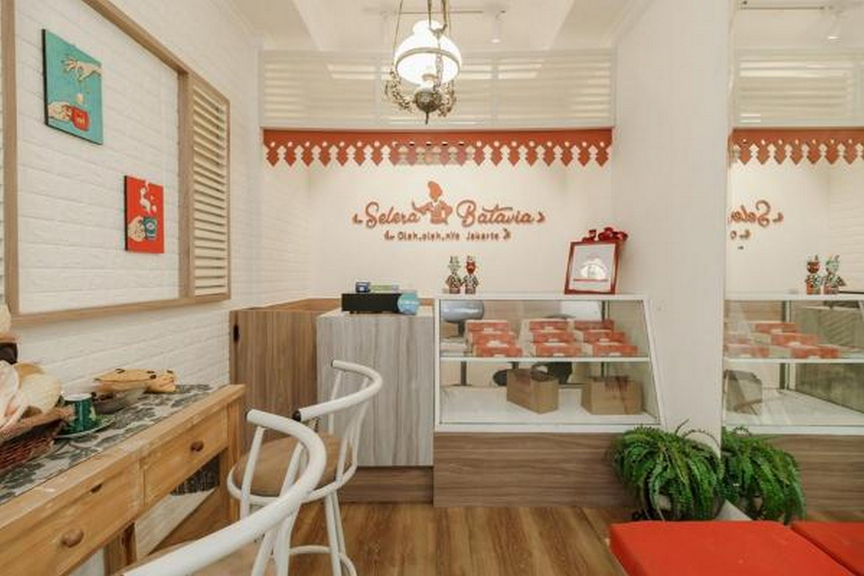 Un cafè acollidor amb un taulell de fusta, tamborets blancs i una vitrina plena de pastissos.