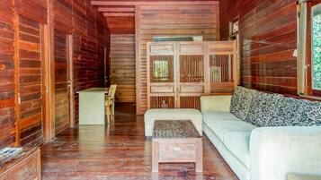 A wooden cabin interior with a sofa, a small table, and a wooden cabinet.