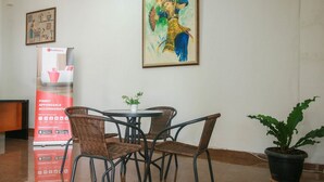 A lobby with a round table, wicker chairs, a potted plant, and a RedDoorz advertisement. - RedDoorz Syariah near Universitas Jenderal Soedirman (Purwokerto)