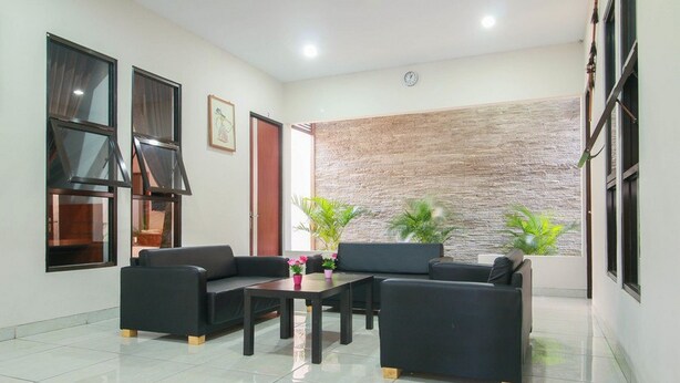 A modern living room with a sofa set, a coffee table, and potted plants. - RedDoorz Syariah near Universitas Jenderal Soedirman (Purwokerto)