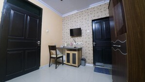 A room with a desk, chair, and a TV mounted on the wall. - RedDoorz Syariah near RSUD Ainun Habibie Gorontalo (Limboto)