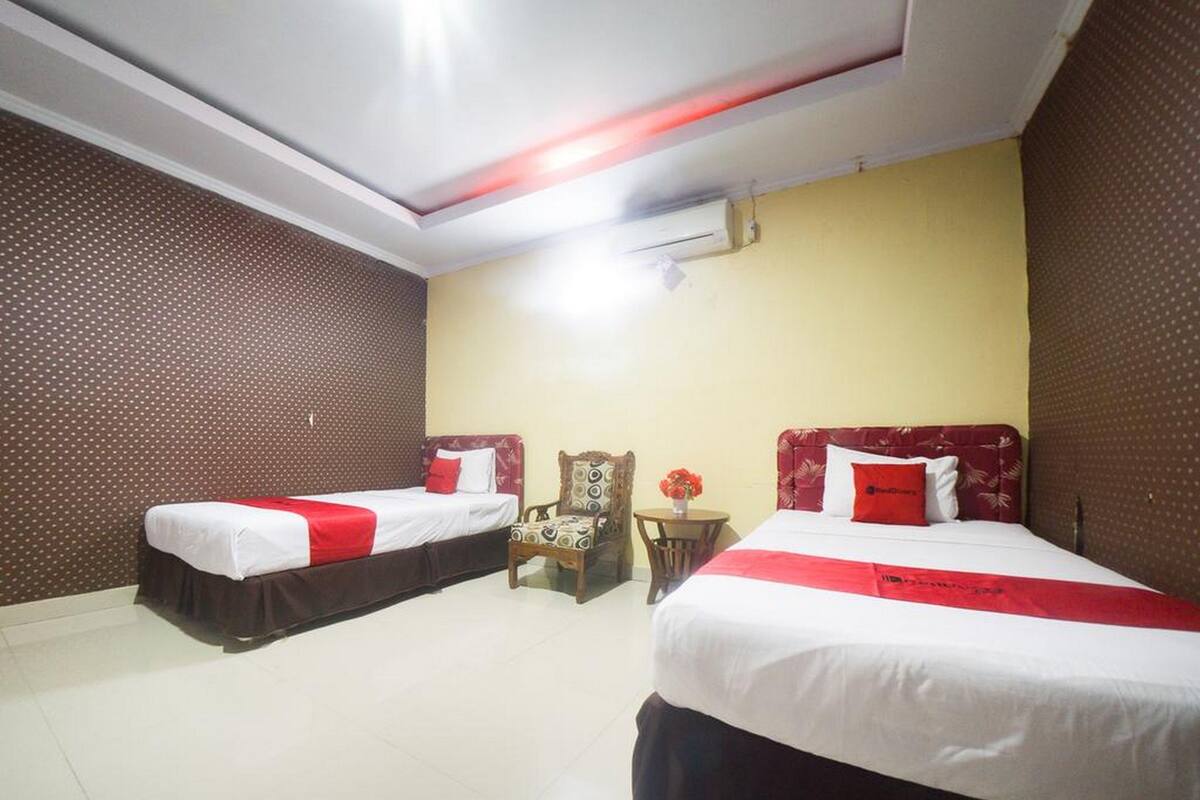 Una habitación de hotel con dos camas, una mesita con un jarrón y una silla.