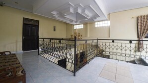A spacious room with a high ceiling, a balcony with a wrought iron railing, and a door leading to another area. - RedDoorz Syariah near RSUD Ainun Habibie Gorontalo (Limboto)