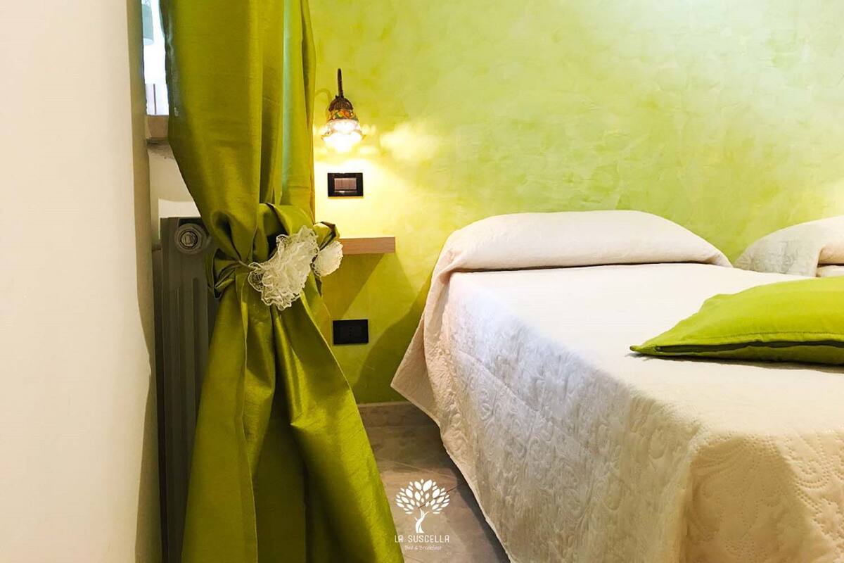 A room with a bed, a nightstand, and a green curtain.