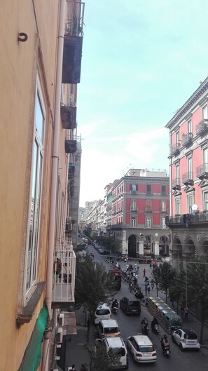 A street view with buildings, vehicles, and pedestrians. - Piano Nobile (Naples)