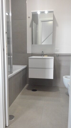 A bathroom with a white sink, mirror, and toilet. - Piano Nobile (Naples)