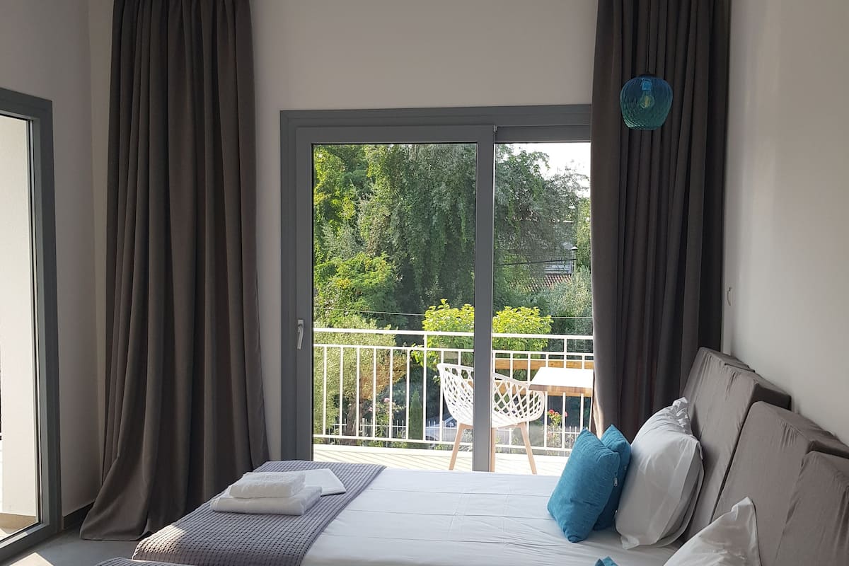 Ein Schlafzimmer mit zwei Betten, einem Balkon und Blick auf Grünflächen.