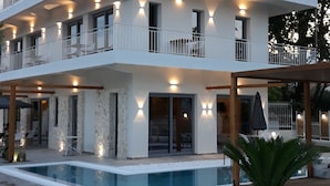 Un hotel de varios pisos con balcones, piscina y zonas de estar al aire libre.