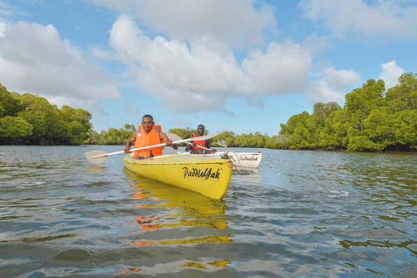 A yellow kayak with 'Paddlejak' written on it, two people paddling, surrounded by calm water and greenery. - Kizingo Beach Eco Lodge (Lamu)