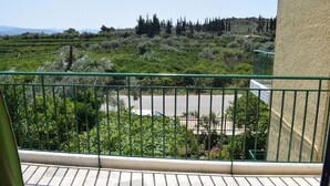 A balcony with a view of a green landscape, including trees and a road. - Apartments Rania (Nafplio)