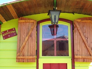 A building with a green facade, a red door, and wooden shutters. A sign on the wall reads "MADALENA".