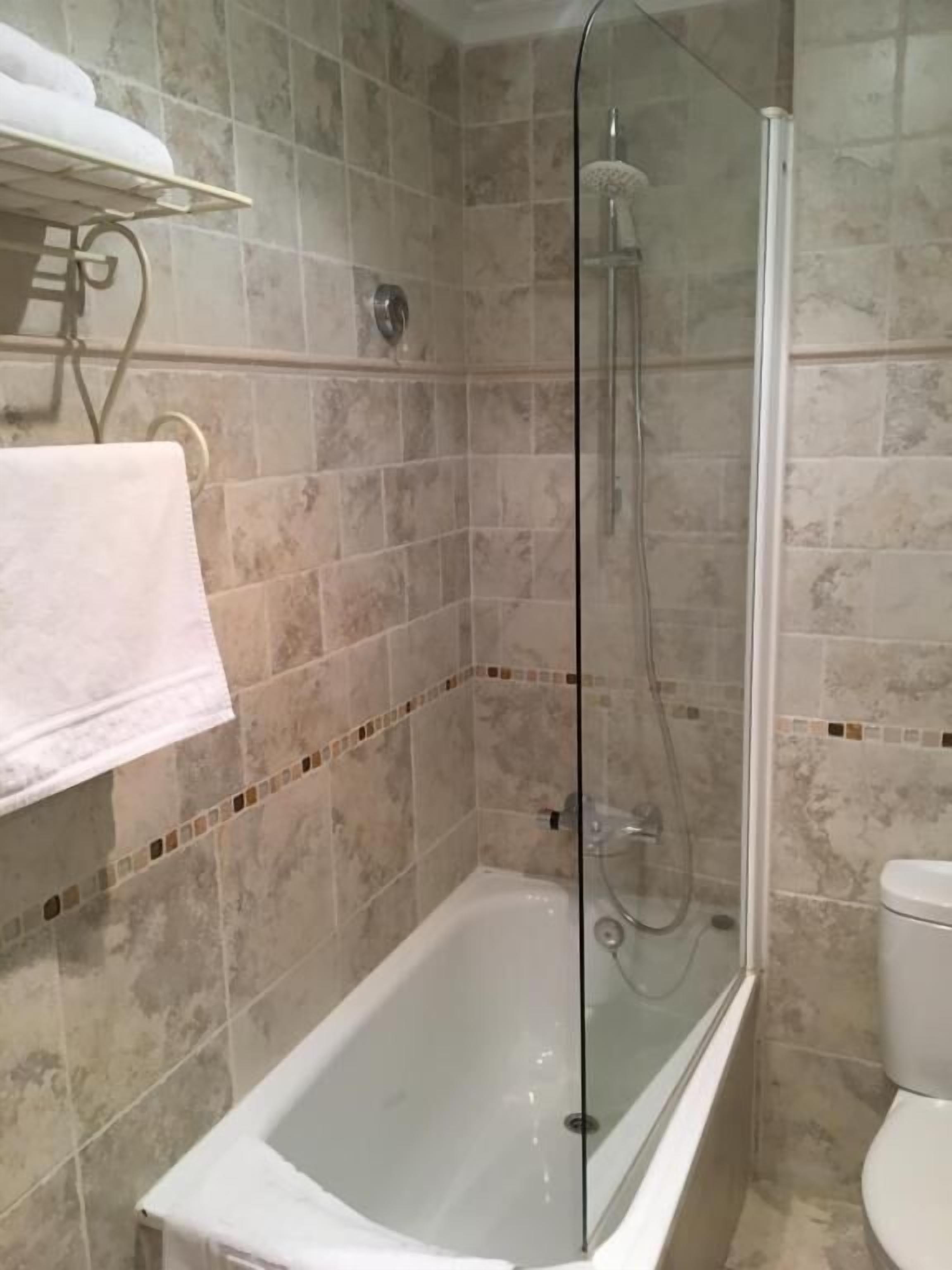 Une salle de bain avec une douche à parois de verre, une baignoire et des toilettes.