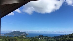 Vista costera desde un espacio cubierto, con cielo despejado y montañas a lo lejos.
